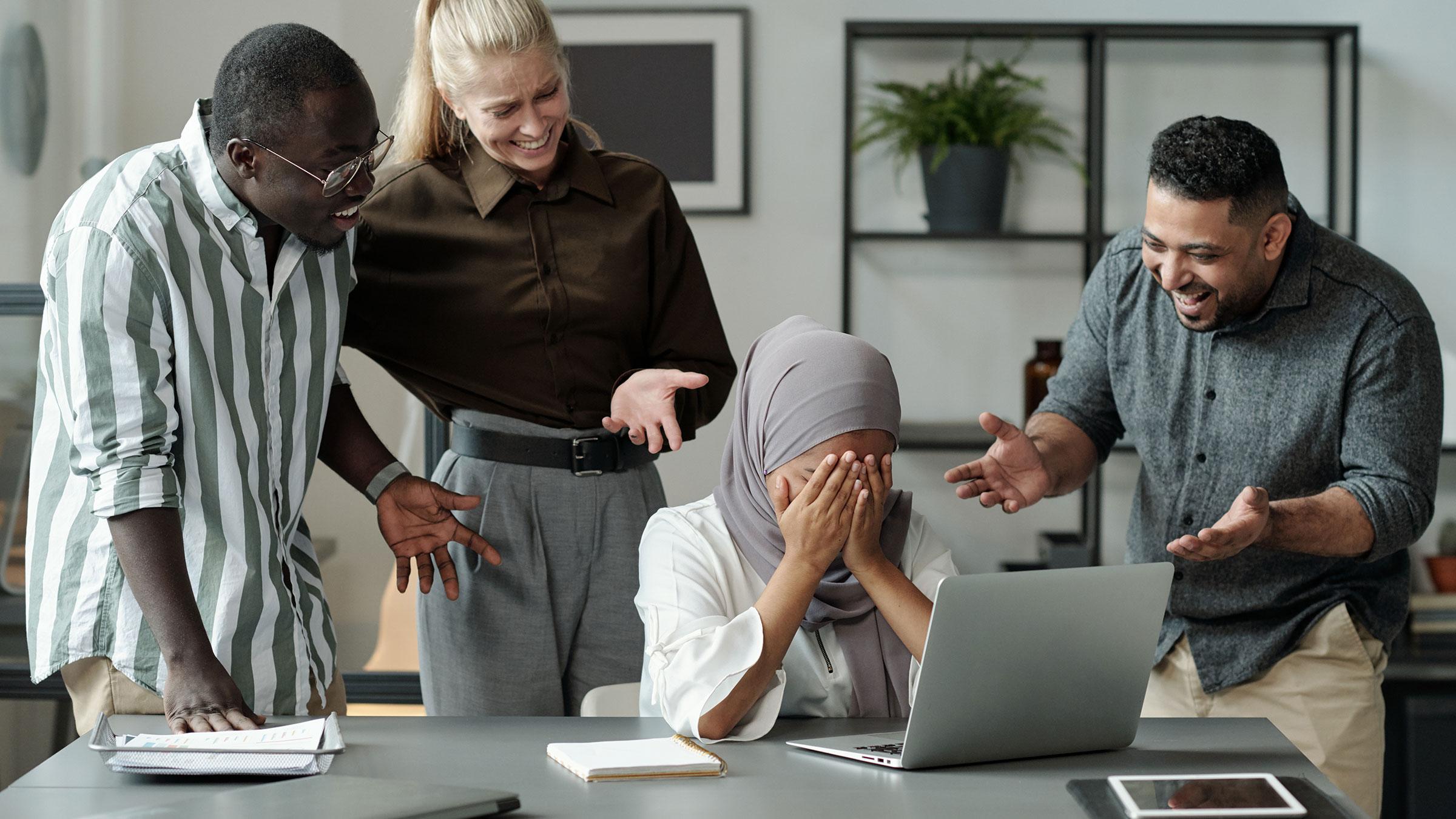 Group of people laughing at a distraught colleague