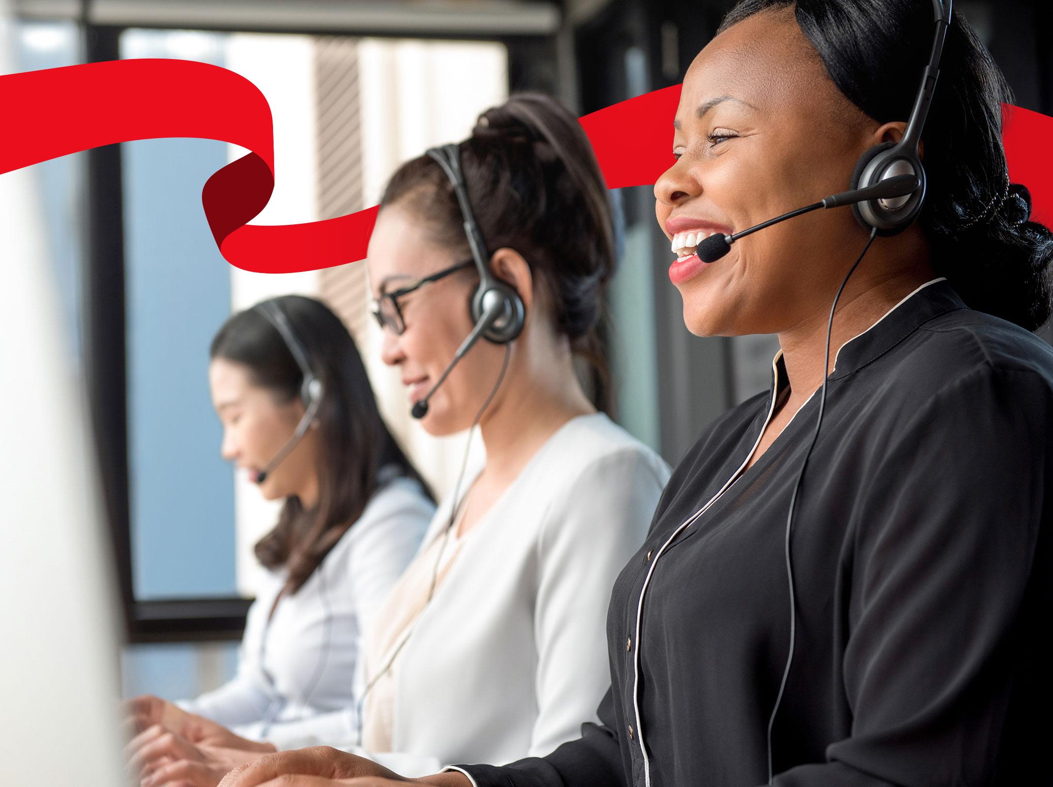 Three sales professionals speaking on headsets in front of computers.